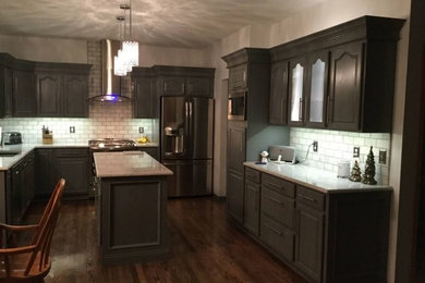 Example of a mid-sized classic u-shaped medium tone wood floor and brown floor eat-in kitchen design in Other with a double-bowl sink, raised-panel cabinets, gray cabinets, white backsplash, stainless steel appliances, an island, subway tile backsplash and white countertops