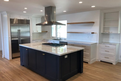 Mid-sized transitional l-shaped light wood floor and brown floor eat-in kitchen photo in Orange County with an undermount sink, recessed-panel cabinets, white cabinets, granite countertops, white backsplash, ceramic backsplash, stainless steel appliances, an island and white countertops