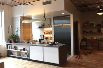 Mid-sized minimalist u-shaped brown floor open concept kitchen photo in New York with a single-bowl sink, flat-panel cabinets, black cabinets, beige backsplash, an island and beige countertops