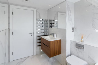 Inspiration for a contemporary bathroom in London with a wall-mount toilet, white tile and marble.