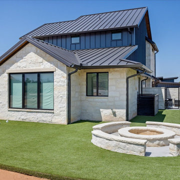 Close-up of a home’s backyard featuring a circular stone fire pit and artificial