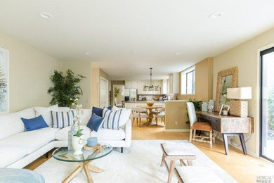 Example of a mid-sized transitional open concept light wood floor family room design in San Francisco with beige walls, a standard fireplace and a wall-mounted tv