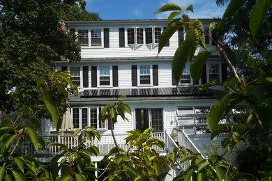 This is an example of a large beach style three-storey white house exterior in New York with wood siding and a shingle roof.