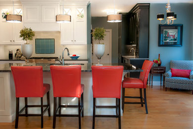 Example of a large transitional galley medium tone wood floor open concept kitchen design in New York with an undermount sink, recessed-panel cabinets, white cabinets, granite countertops, white backsplash, ceramic backsplash, stainless steel appliances and an island