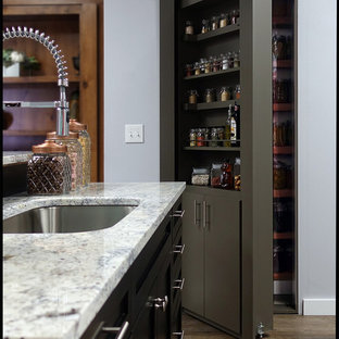 Inspiration för stora grått skafferier, med en enkel diskho, släta luckor, grå skåp, granitbänkskiva, svart stänkskydd, rostfria vitvaror, linoleumgolv och brunt golv