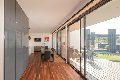 Mid-sized modern dining room in Geelong with white walls and painted wood floors.