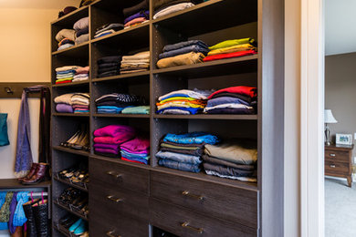 Mid-sized contemporary gender-neutral walk-in wardrobe in Vancouver with flat-panel cabinets, dark wood cabinets and carpet.