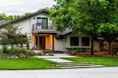 Photo of a huge modern partial sun front yard stone and wood fence landscaping in Denver.