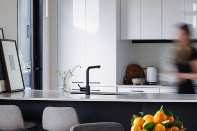Design ideas for a small galley kitchen in Melbourne with an undermount sink, white cabinets, quartz benchtops, white splashback, engineered quartz splashback, white appliances, a peninsula, white benchtop and vaulted.