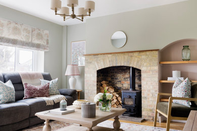 Farmhouse living room in Other with green walls, medium hardwood flooring, a wood burning stove and brown floors.