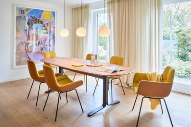 Mid-Century Esszimmer mit hellem Holzboden, weißer Wandfarbe und beigem Boden in München
