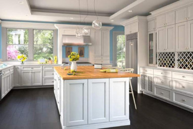 Example of a large transitional u-shaped dark wood floor and black floor open concept kitchen design in Other with an undermount sink, recessed-panel cabinets, white cabinets, wood countertops, stainless steel appliances, an island and beige countertops