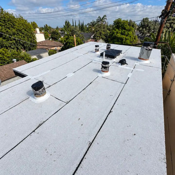 White cap sheet on the ADU flat roof, vents flashed and sealed