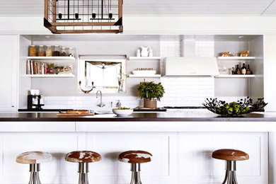 Design ideas for a large country galley open plan kitchen in Melbourne with a farmhouse sink, shaker cabinets, white cabinets, wood benchtops, white splashback, ceramic splashback, white appliances, dark hardwood floors, with island and grey benchtop.