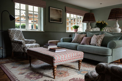 Inspiration for a medium sized eclectic formal enclosed living room in Sussex with green walls, medium hardwood flooring, a wood burning stove, a brick fireplace surround, a wall mounted tv, brown floors, panelled walls and a dado rail.