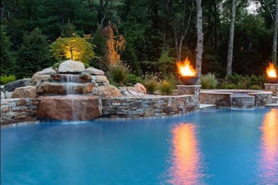 Diseño de piscina elevada grande en patio trasero con paisajismo de piscina y adoquines de ladrillo