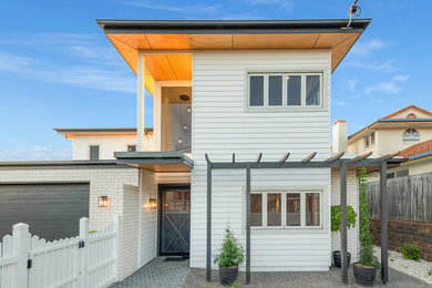 Photo of a large contemporary two-storey brick white house exterior in Sunshine Coast with a hip roof and a metal roof.