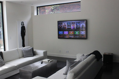 This is an example of a mid-sized modern open concept family room in Toronto with white walls, dark hardwood floors, a two-sided fireplace, a plaster fireplace surround, a wall-mounted tv and brown floor.