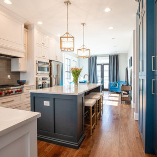 Exemple d'une arrière-cuisine parallèle éclectique de taille moyenne avec un évier encastré, un placard à porte shaker, des portes de placard turquoises, un plan de travail en quartz modifié, une crédence grise, une crédence en carreau de céramique, un électroménager en acier inoxydable, un sol en bois clair, un îlot central, un sol marron et un plan de travail blanc.