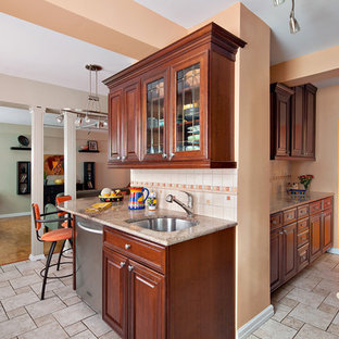 Inspiration for a mid-sized l-shaped kitchen pantry in New York with raised-panel cabinets, medium wood cabinets, granite benchtops, orange splashback, an undermount sink, porcelain splashback, stainless steel appliances, ceramic floors and no island.