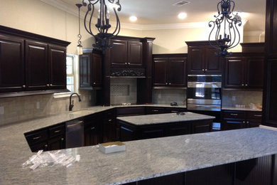 Inspiration for a mid-sized eclectic u-shaped ceramic tile eat-in kitchen remodel in Other with an undermount sink, raised-panel cabinets, black cabinets, granite countertops, brown backsplash, ceramic backsplash, stainless steel appliances and an island