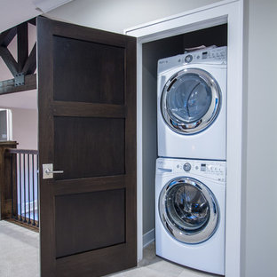 Small classic laundry cupboard in Omaha with carpet and a stacked washer and dryer.