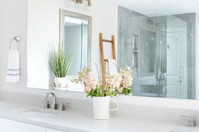 Photo of a large traditional ensuite bathroom in Vancouver with shaker cabinets, white cabinets, a freestanding bath, a corner shower, a one-piece toilet, grey tiles, porcelain tiles, white walls, porcelain flooring, a built-in sink, engineered stone worktops, white floors, a hinged door, grey worktops, an enclosed toilet, double sinks and a built in vanity unit.