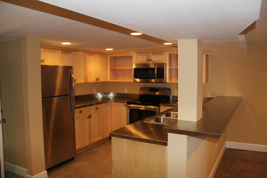 Inspiration for a small timeless l-shaped concrete floor eat-in kitchen remodel in Portland with a double-bowl sink, shaker cabinets, light wood cabinets, stainless steel countertops, beige backsplash, stainless steel appliances and a peninsula