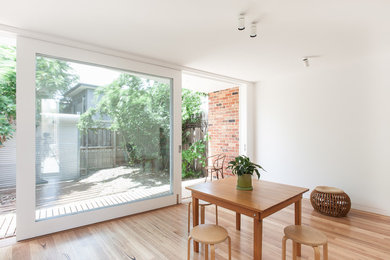 Photo of a contemporary kitchen/dining combo in Melbourne with white walls and medium hardwood floors.