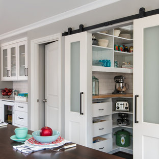 Kleine Klassische Küche in L-Form mit Schrankfronten im Shaker-Stil, weißen Schränken, Küchenrückwand in Weiß, Rückwand aus Metrofliesen, Küchengeräten aus Edelstahl, dunklem Holzboden, Kücheninsel, Landhausspüle, Arbeitsplatte aus Holz, Vorratsschrank, braunem Boden und weißer Arbeitsplatte in Detroit