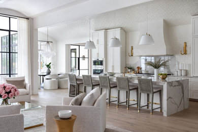 Inspiration for a huge transitional single-wall medium tone wood floor, brown floor and vaulted ceiling open concept kitchen remodel in Houston with a farmhouse sink, recessed-panel cabinets, white cabinets, marble countertops, gray backsplash, marble backsplash, stainless steel appliances, an island and gray countertops