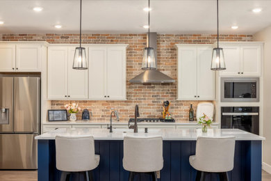 Large mid-century modern eat-in kitchen photo in Boise with recessed-panel cabinets, brick backsplash, an island and white countertops