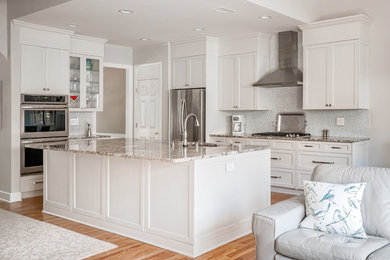 Kitchen - transitional light wood floor kitchen idea in Atlanta with an undermount sink, shaker cabinets, white cabinets, granite countertops, glass tile backsplash, stainless steel appliances and an island