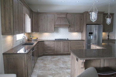 Open concept kitchen - mid-sized transitional l-shaped ceramic tile open concept kitchen idea in Other with an undermount sink, raised-panel cabinets, beige backsplash, subway tile backsplash, stainless steel appliances, an island, medium tone wood cabinets and quartz countertops