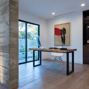 This is an example of a medium sized modern study in San Diego with white walls, light hardwood flooring, no fireplace, a freestanding desk and brown floors.
