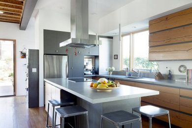 Trendy l-shaped dark wood floor eat-in kitchen photo in Los Angeles with flat-panel cabinets, distressed cabinets, solid surface countertops, stainless steel appliances, an island and gray countertops