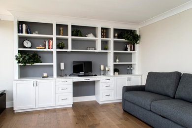 Mid-sized transitional built-in desk medium tone wood floor and brown floor study room photo with white walls