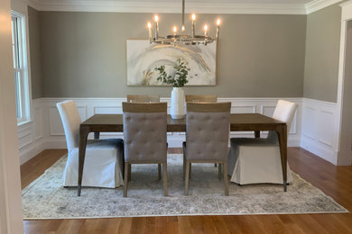 Large transitional medium tone wood floor, tray ceiling and wainscoting enclosed dining room photo in Boston with beige walls