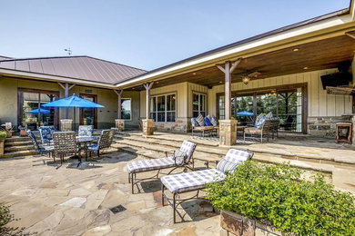 Large mountain style backyard stone patio photo in Austin with a roof extension
