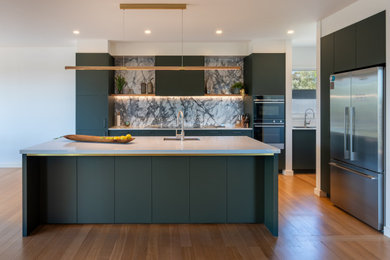 Photo of a mid-sized contemporary kitchen in Melbourne with flat-panel cabinets, green cabinets, stone slab splashback and with island.