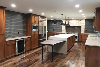 Example of a large arts and crafts u-shaped medium tone wood floor eat-in kitchen design in Seattle with an undermount sink, shaker cabinets, dark wood cabinets, quartzite countertops, gray backsplash, ceramic backsplash, stainless steel appliances and an island