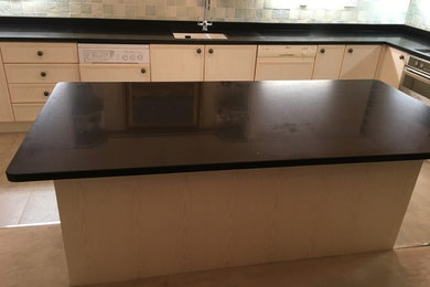 This is an example of a mid-sized traditional l-shaped separate kitchen in Other with a double-bowl sink, quartzite benchtops, with island and black benchtop.