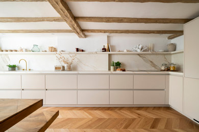 Photo of a medium sized contemporary l-shaped kitchen/diner in Berkshire with a built-in sink, beige cabinets, composite countertops, white splashback, medium hardwood flooring, no island, white worktops, exposed beams and a chimney breast.