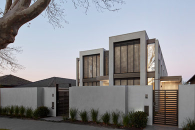 This is an example of a mid-sized contemporary two-storey concrete grey duplex exterior in Melbourne with a flat roof and a metal roof.