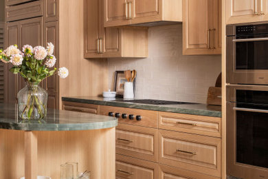 Example of a beach style galley light wood floor kitchen design in San Diego with raised-panel cabinets, light wood cabinets, an island, an undermount sink, quartzite countertops, white backsplash, ceramic backsplash, stainless steel appliances and green countertops
