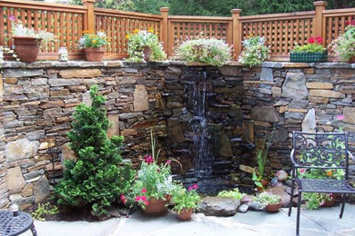This is an example of a mid-sized traditional drought-tolerant and full sun courtyard stone water fountain landscape in Baltimore.