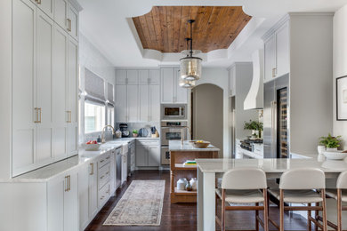 Example of a mid-sized transitional u-shaped medium tone wood floor eat-in kitchen design in Austin with an undermount sink, shaker cabinets, white cabinets, granite countertops, stainless steel appliances, an island and white countertops