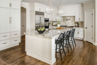 Mid-sized transitional medium tone wood floor eat-in kitchen photo in Charlotte with white cabinets, quartzite countertops, beige backsplash, stone slab backsplash, stainless steel appliances, an island and beige countertops