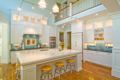 Example of a mid-sized classic l-shaped medium tone wood floor and brown floor open concept kitchen design in Salt Lake City with an undermount sink, recessed-panel cabinets, white cabinets, solid surface countertops, blue backsplash, subway tile backsplash, an island and paneled appliances