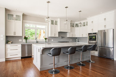 Large elegant l-shaped medium tone wood floor and brown floor open concept kitchen photo in Vancouver with an undermount sink, shaker cabinets, white cabinets, quartz countertops, gray backsplash, ceramic backsplash, stainless steel appliances, an island and gray countertops